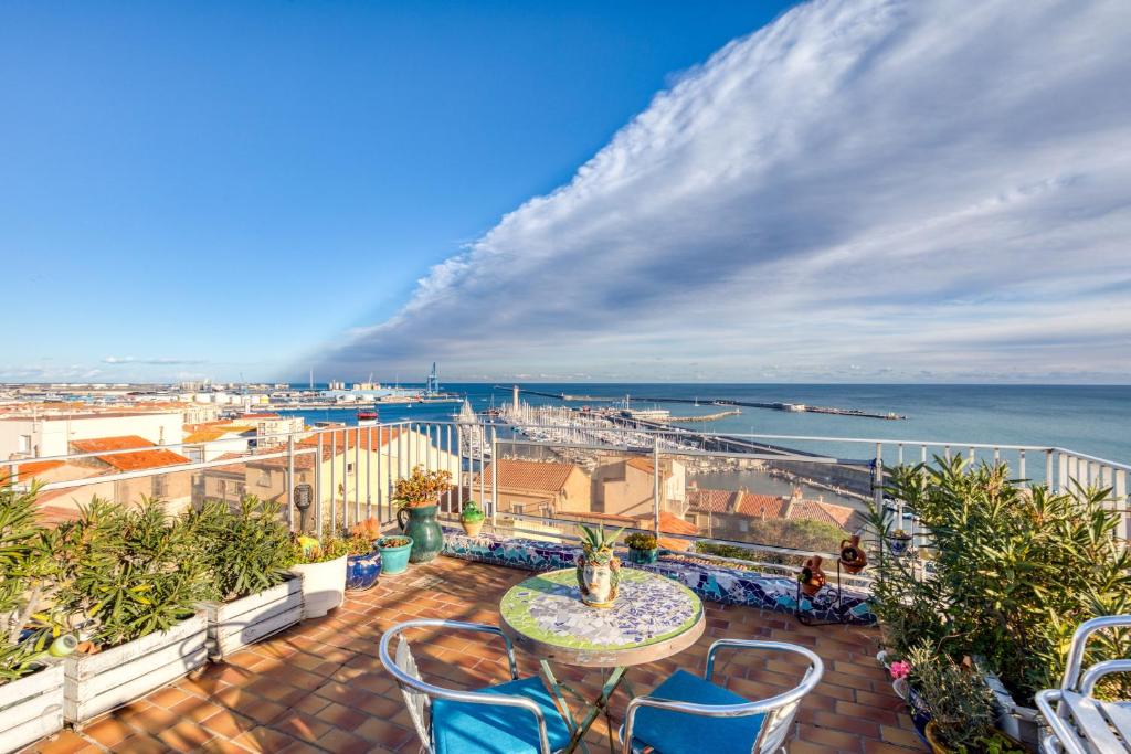 un balcon avec une table et des chaises et l'océan dans l'établissement Chambre d'hôtes - Le quartier haut, à Sète
