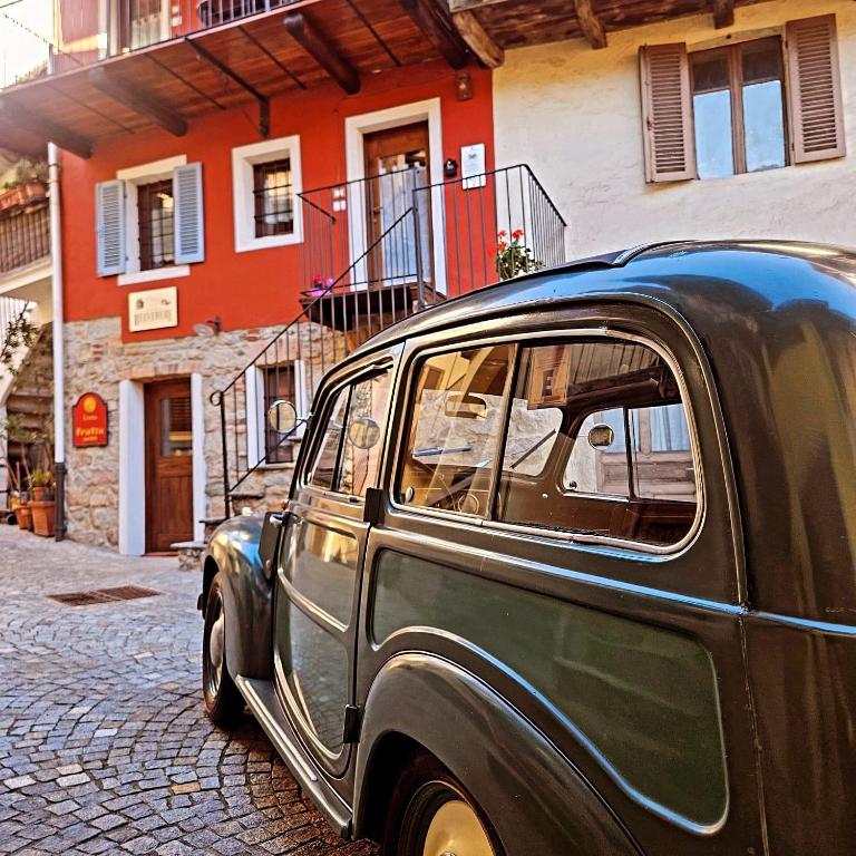 an old green car parked on a cobblestone street at Belvedere Apartments Valdilana in Trivero