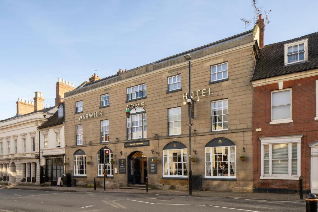 a large brick building on the corner of a street at The Warwick Arms Hotel - The Coaching Inn Group in Warwick
