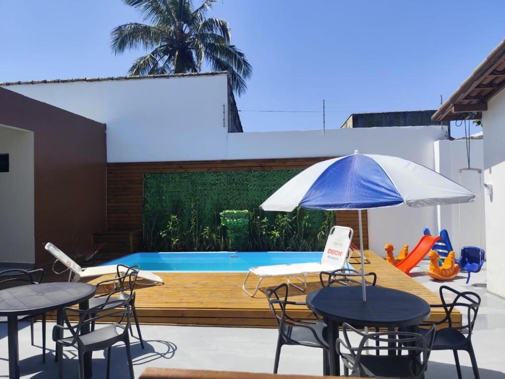a patio with tables and chairs and a swimming pool at Pousada Esspaço Vista Mar in Itanhaém