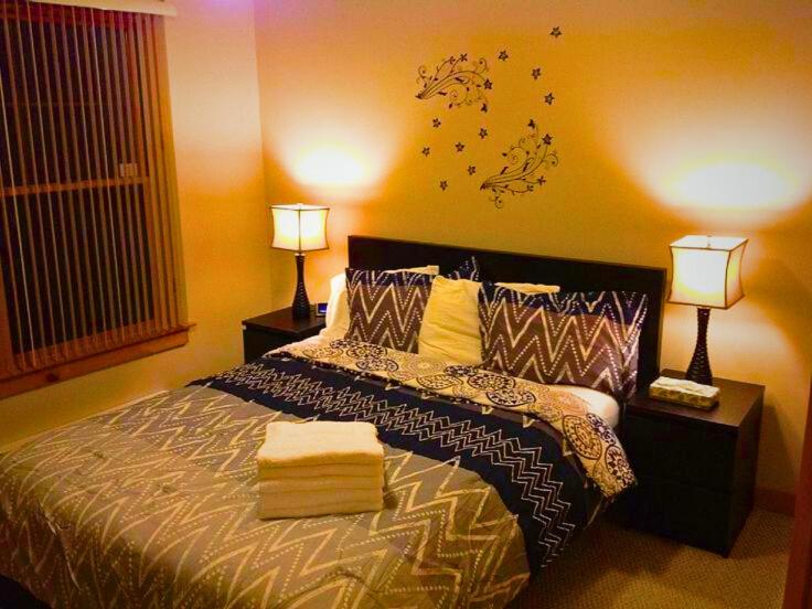 Un dormitorio con una cama con dos lámparas encima. en The Golden Suite, en Islamabad