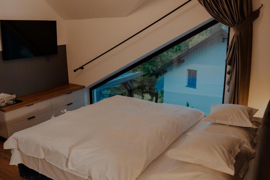 a bedroom with a white bed and a large window at Pensiunea CityView in Câmpulung Moldovenesc