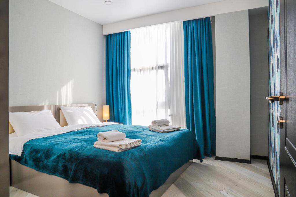 Un dormitorio con una cama con sábanas azules y una ventana. en Hotel Qumli Apartment with mountain views, en Kʼumlistsʼikhe