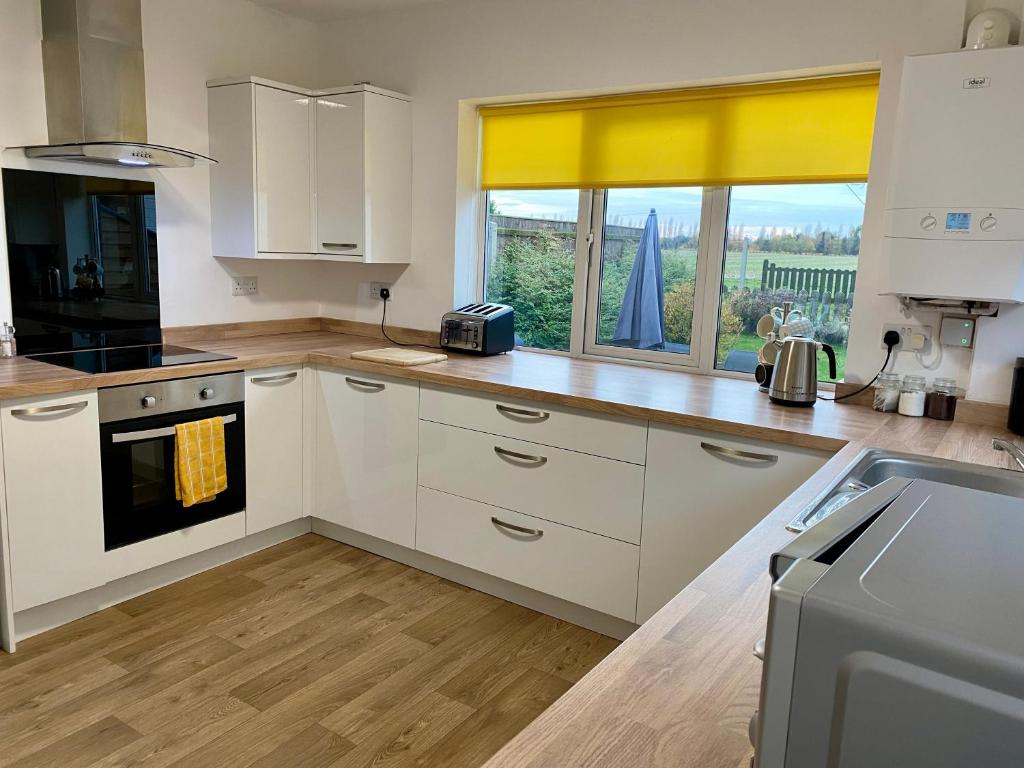 a kitchen with white cabinets and a large window at Simla Bungalow, Tetney, Spacious Parking, Private Garden in Tetney