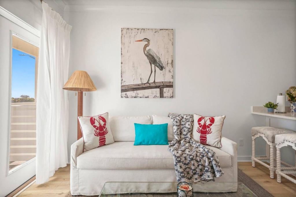 a living room with a white couch and a bird picture on the wall at Extended Stay Friendly-Full Kitchen & Laundry in Pass Christian