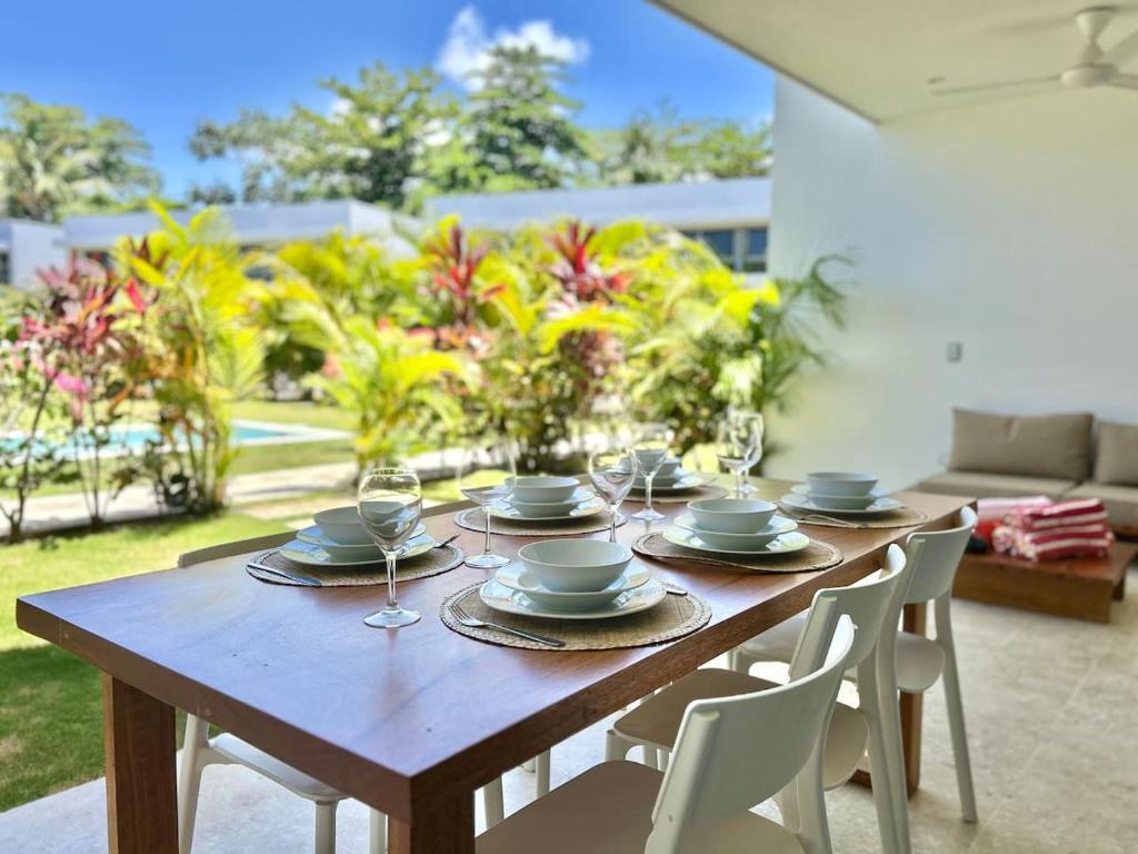 a wooden table with plates and wine glasses on it at Villa Hazel in Las Terrenas