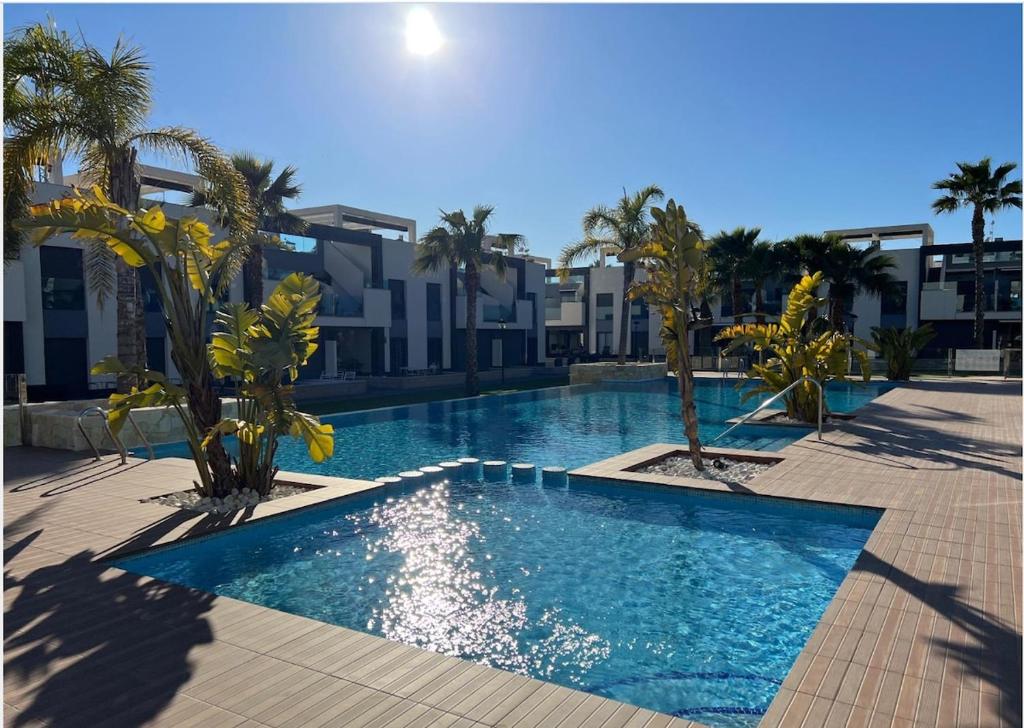 a swimming pool with palm trees and buildings at Flamingo del Guardamar in Guardamar del Segura