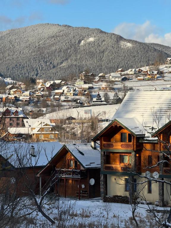 una casa en la nieve con una montaña en el fondo en Близнюки Готель, en Vorokhta