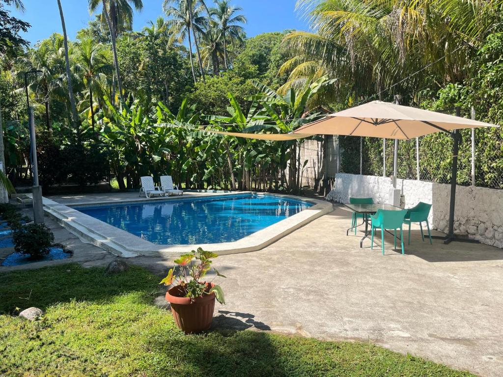 una piscina con ombrellone e tavolo e sedie di Rancho el Cocalito a La Libertad