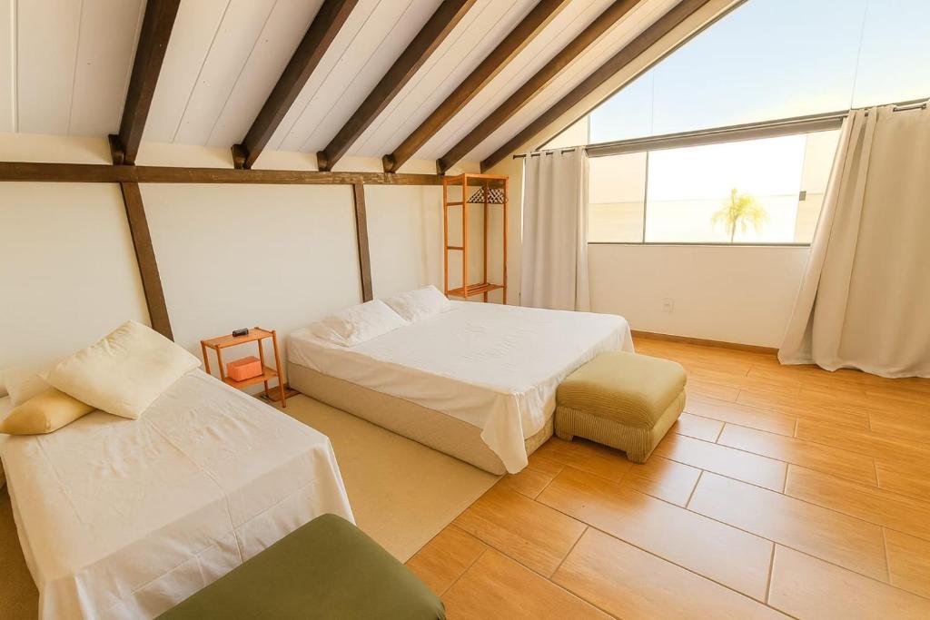 a bedroom with two beds and a couch and a window at Pousada Morada Coqueiros in Florianópolis