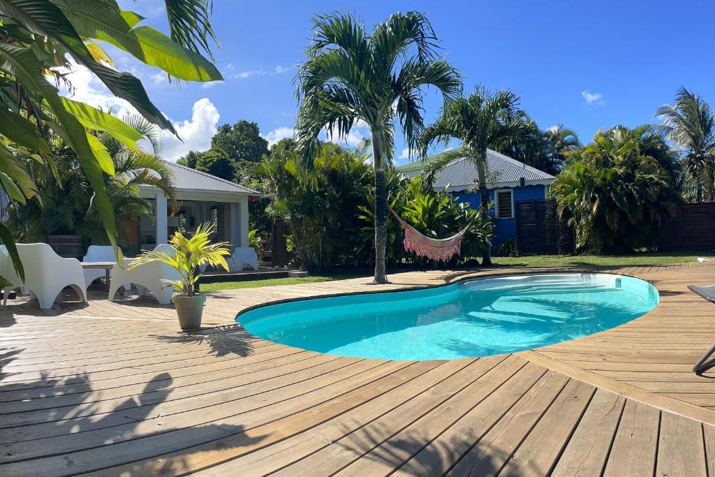 a swimming pool on a wooden deck next to a house at Au son des Grenouilles in Sainte-Rose