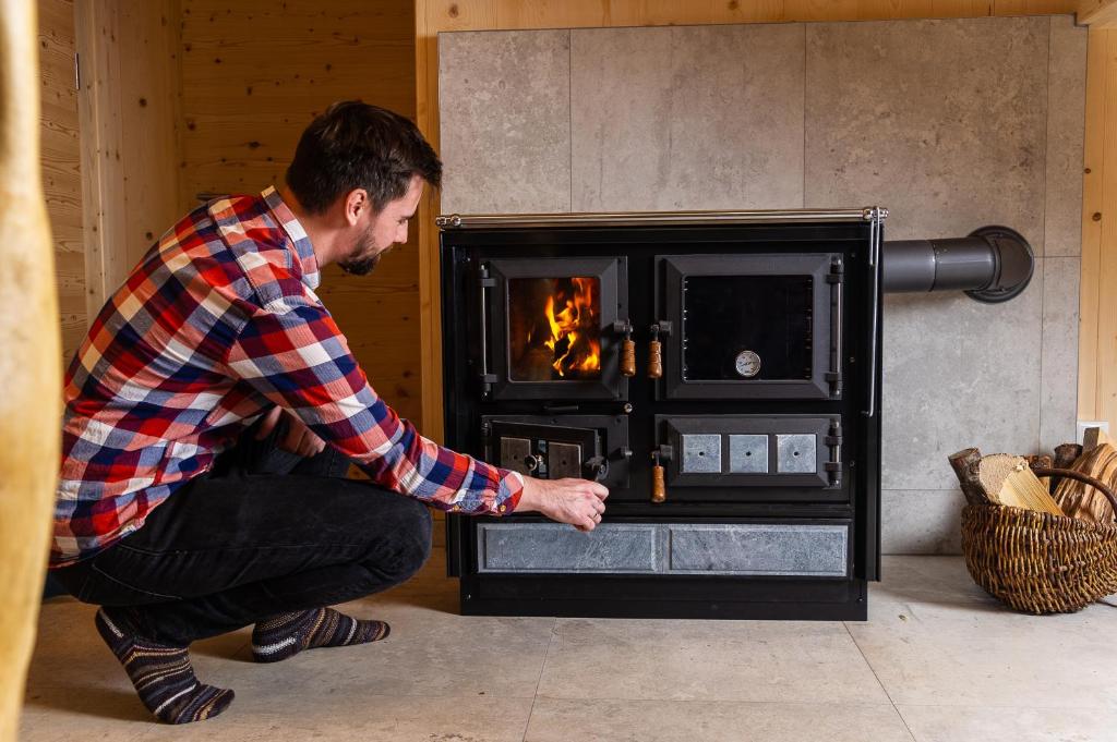 a man squatting in front of a fireplace at Ferienhaus Blauer Vogel - kostenfreie Saunanutzung in Prägraten