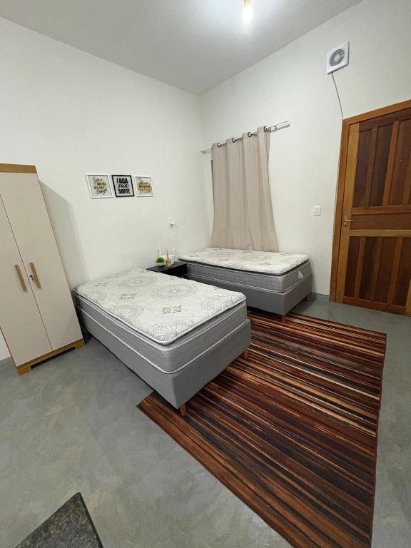 two beds sitting in a room with a rug at Studio 4 - Solteiro in Aracruz