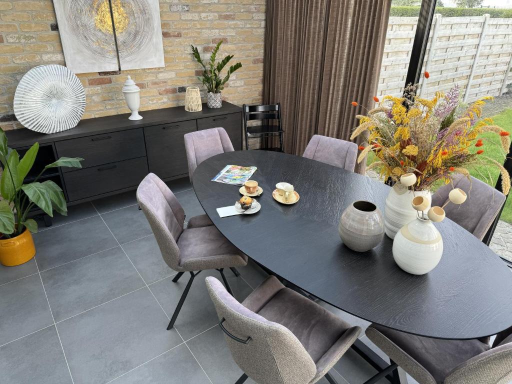 a black table with chairs and vases on it at De Kruishoeve in De Haan