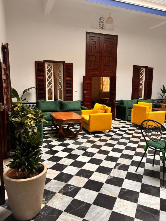 a living room with yellow and green furniture on a checkered floor at Riad Rabat Laalou in Rabat