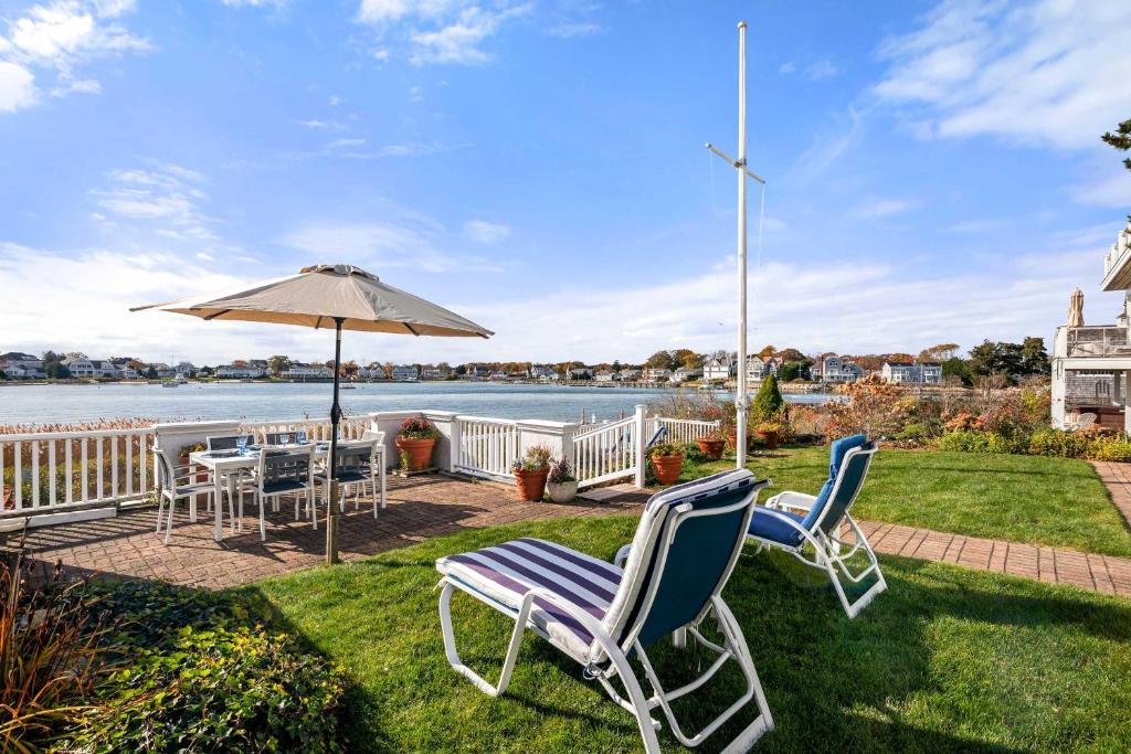 Un patio con sillas, una mesa y una sombrilla. en Waterfront Private Beach Gorgeous Views, en Hyannis