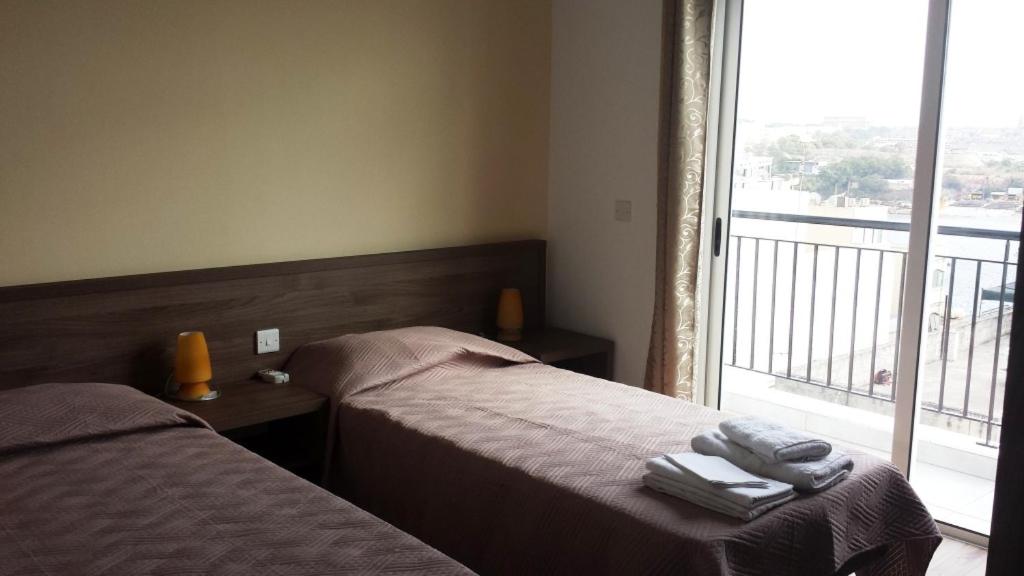 two beds in a hotel room with a window at AM Apartments in Sliema