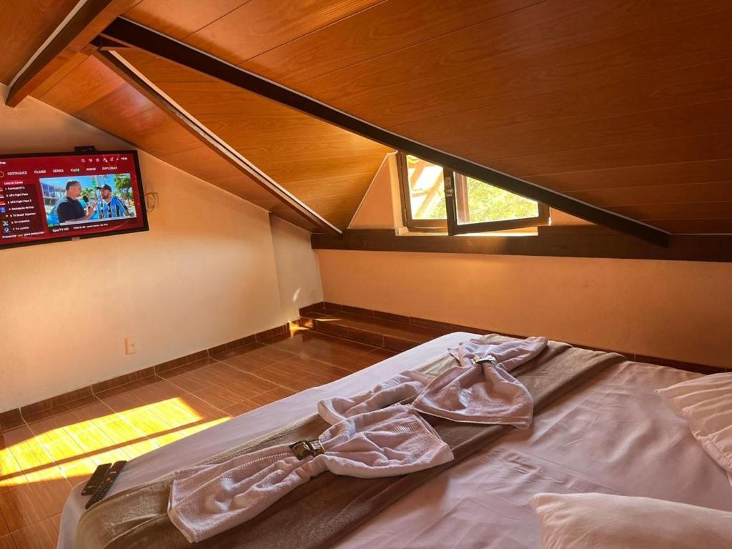 ein Schlafzimmer mit einem Bett und einem Fernseher an der Wand in der Unterkunft Pousada Rio Cipó in Serra do Cipo