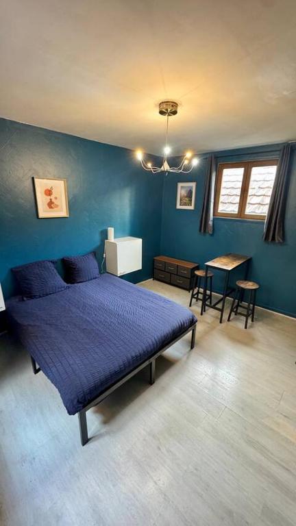 - une chambre bleue avec un lit et une table dans l'établissement Cosy 5 - Montbéliard, à Montbéliard