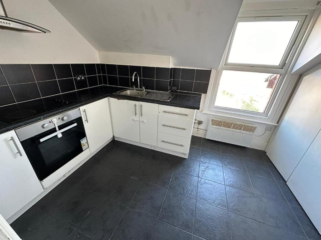 a kitchen with white cabinets and a sink and a window at Smart 2 bed apartment in Purley