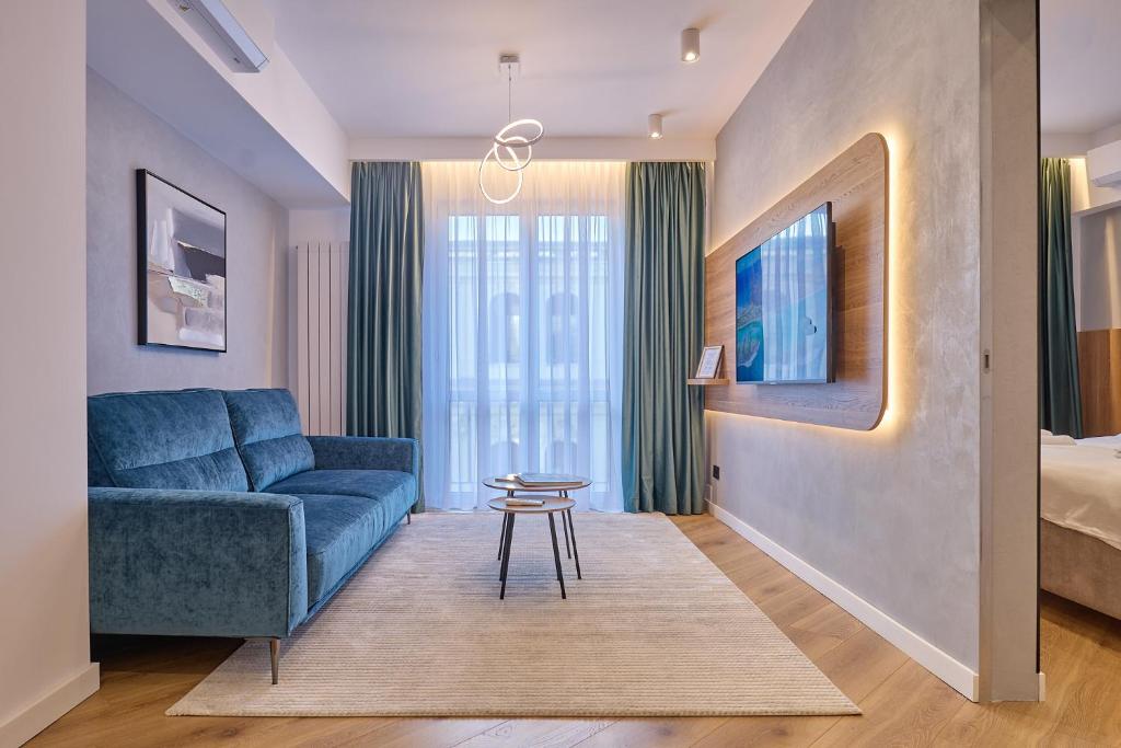 a living room with a blue couch and a bed at CHANTTAL Luxury - ACADEMY in Bucharest