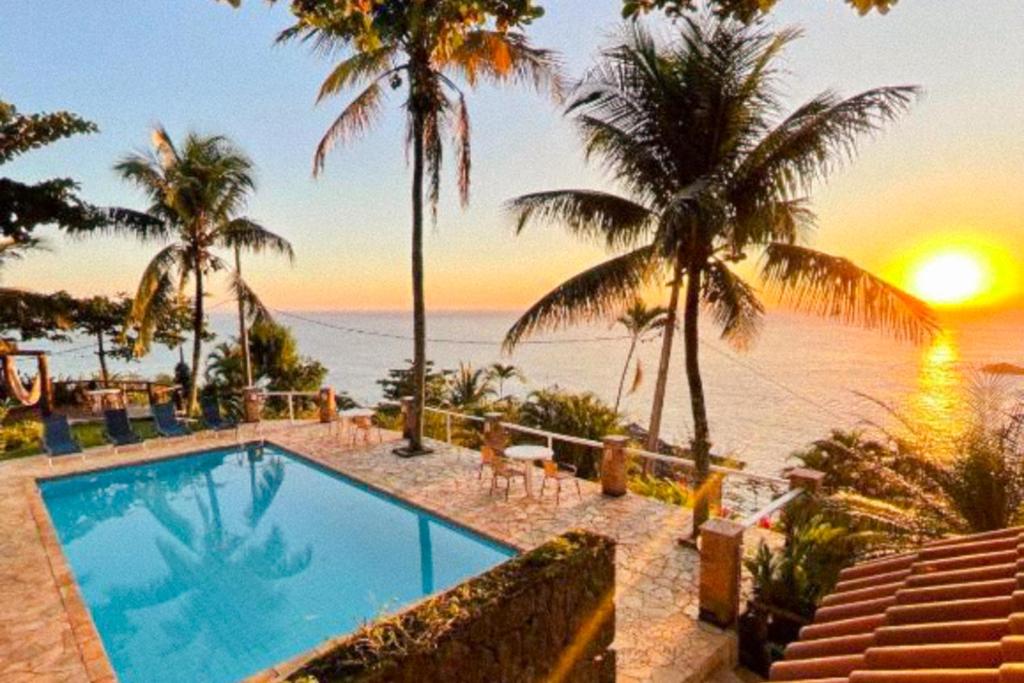 ein Swimmingpool neben dem Strand mit Sonnenuntergang in der Unterkunft VELINN Pousada 8 Ilhas in Ilhabela