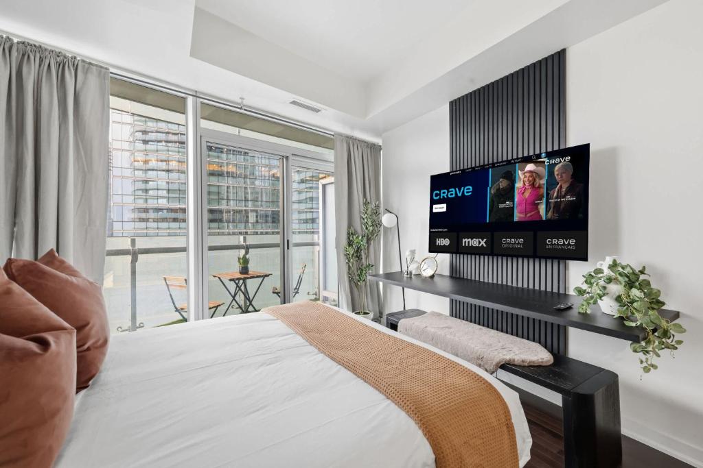 a bedroom with a bed and a flat screen tv at Stylish Downtown Studio with CN Tower Views in Toronto