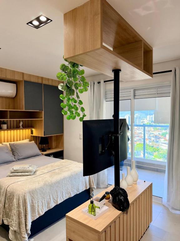 a bedroom with a bed and a tv on a table at Studio 107 Home Com Varanda, Ar-condicionado e Netflix in Mogi das Cruzes