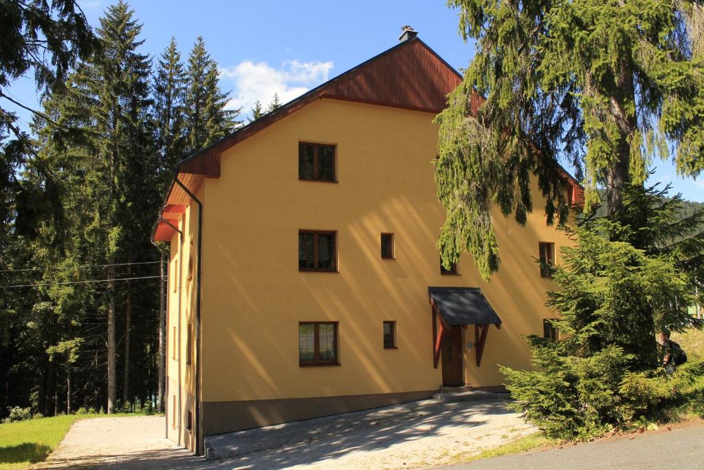 a large yellow building with a red roof at Apartmány Olympia in Železná Ruda