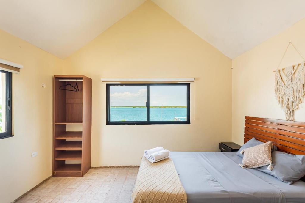 ein Schlafzimmer mit großem Bett und Fenster in der Unterkunft Casa Sirena - Habitaciones a orilla de la Laguna y Cenote Esmeralda in Bacalar