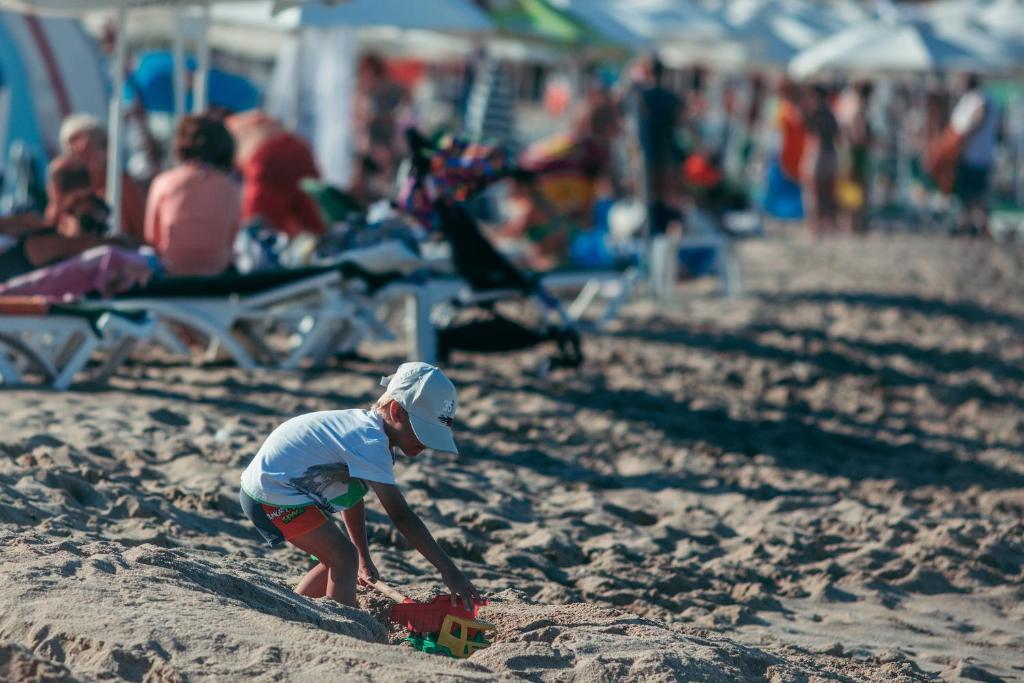 a small child playing in the sand at the beach at Green Life Apartments Sozopol in Sozopol