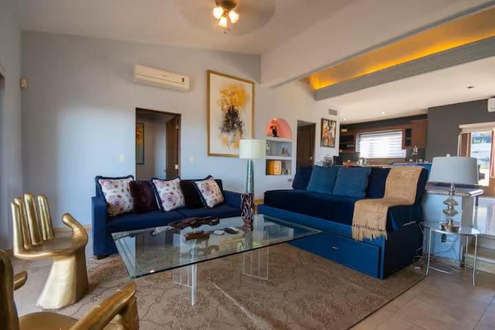a living room with a blue couch and a glass table at Casa Reyes -All in One, Heated Pool & Beach Access in El Pueblito