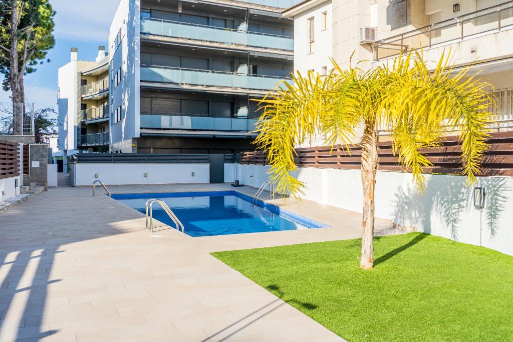 palma di fronte a un edificio con piscina di Hauzify I Apartaments Coral a Torredembarra