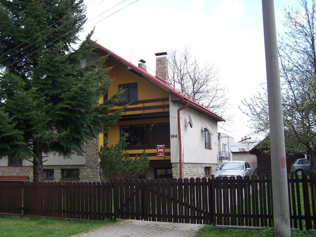 una casa amarilla y blanca con una valla en Robotnícka ubytovňa Bodice 104, en Liptovský Mikuláš