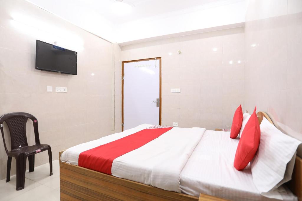 范兰德凡Hotel O Shree Raghuvar Dham的一间卧室配有一张带红色枕头的床和一台电视。