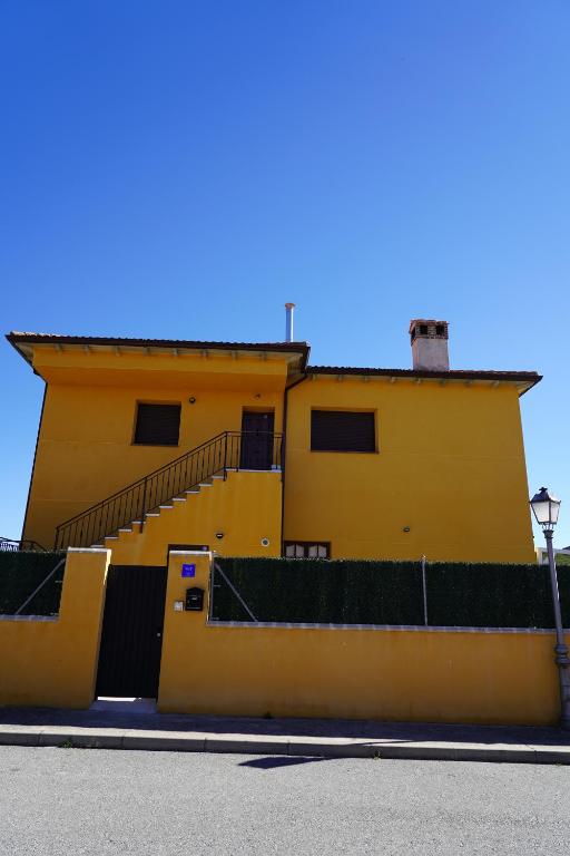 a yellow building with stairs on the side of it at El Mirador de Segovia in Basardilla