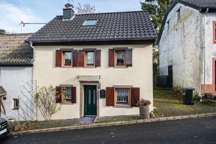 una casa bianca con una porta verde su una strada di Ferienhaus Auf dem Knapp 