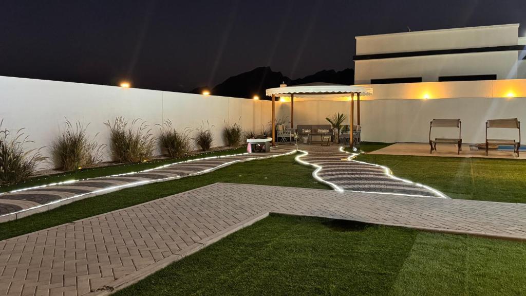 een tuin 's nachts met een pad en een gebouw bij Bain Al Qimam in Hatta