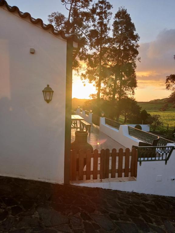a white building with a fence and a sunset at Casa da VíVí in Azenha de Baixo