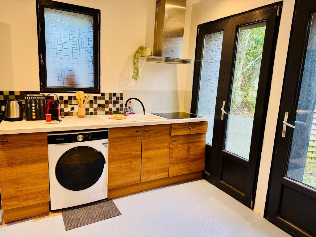 een keuken met een wasmachine, een wastafel en een fornuis bij Duplex Montmorency à 30min de Paris in Montmorency