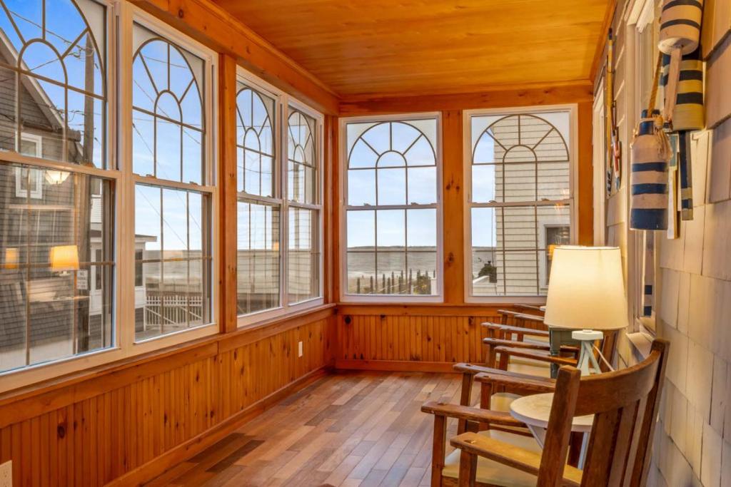 een kamer met ramen en een tafel en stoelen bij Danemead Cottage - For 10ppl in Old Orchard Beach