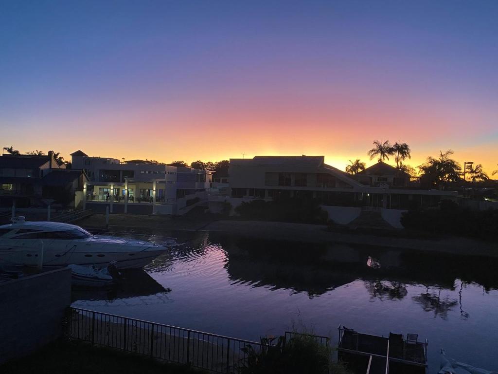 Una puesta de sol sobre un cuerpo de agua con casas y barcos. en Relaxation room on super cool side of house, en Gold Coast