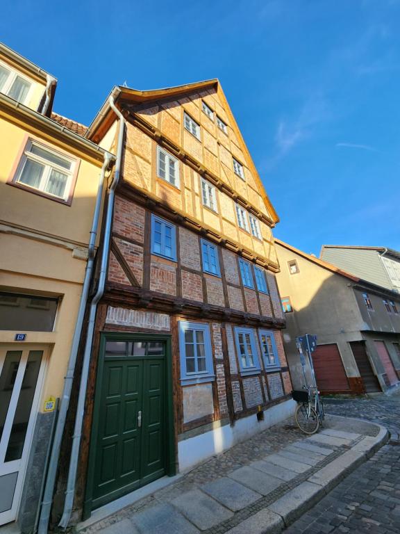 a wooden building with a green door on a street at Fachwerkzeit Haus mit zwei Apartments in Quedlinburg