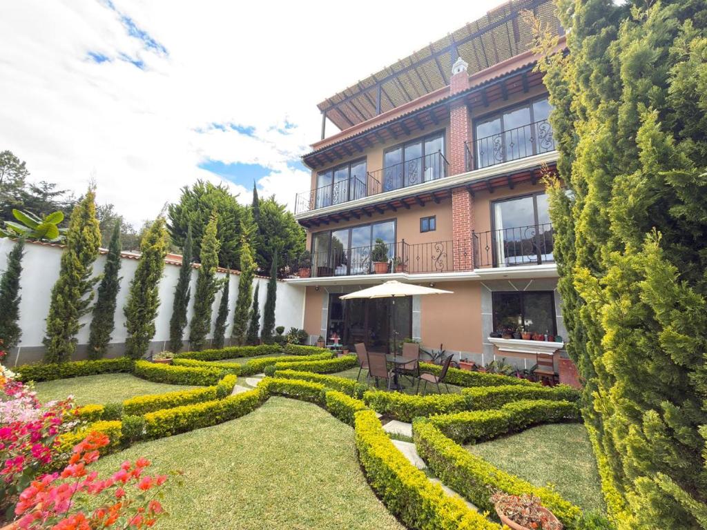 a building with a garden with a hedge at Hotel y Restaurante Vista Verde in Santa Lucía Milpas Altas