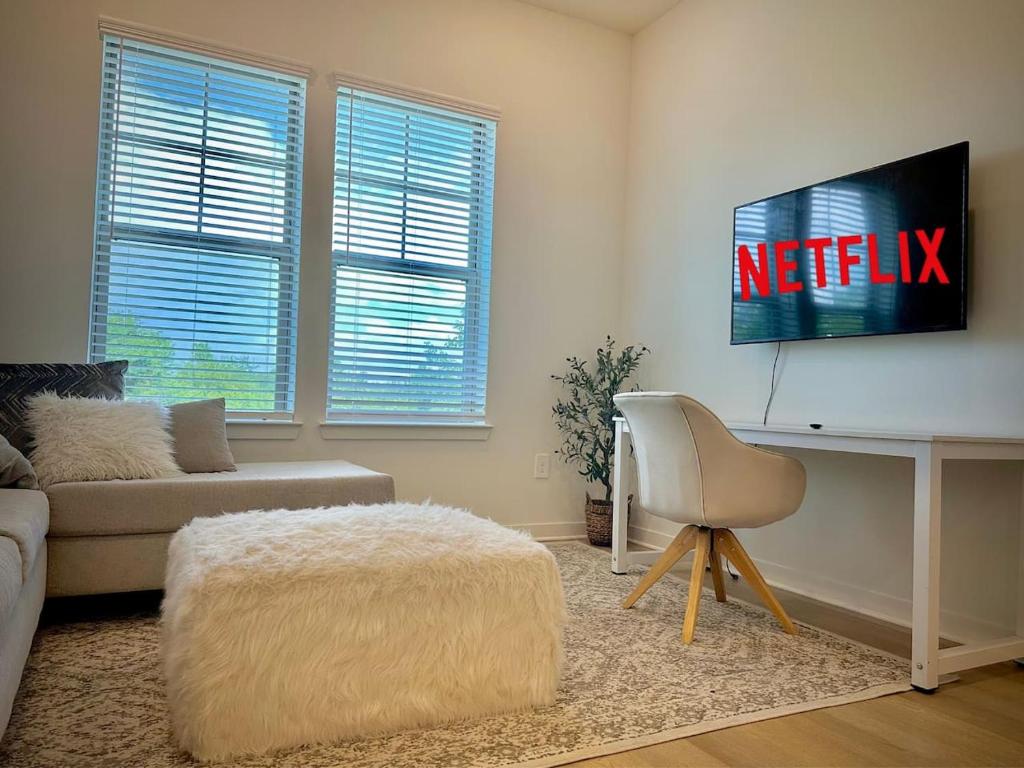 een woonkamer met een bank en een tv aan de muur bij Modern WorkerFriendly WasherPoolGym Wifi in Sherman