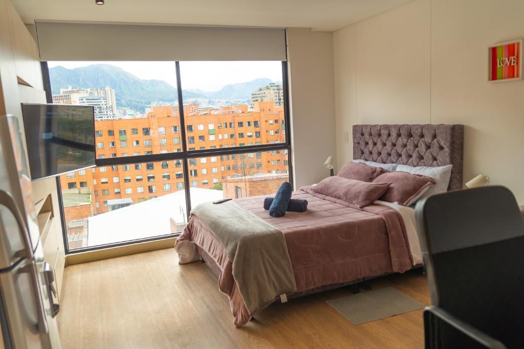 ein Schlafzimmer mit einem Bett und einem großen Fenster in der Unterkunft Corferias Embajada Usa Centro Aeropuerto Mascotas Coliving Coworking in Bogotá