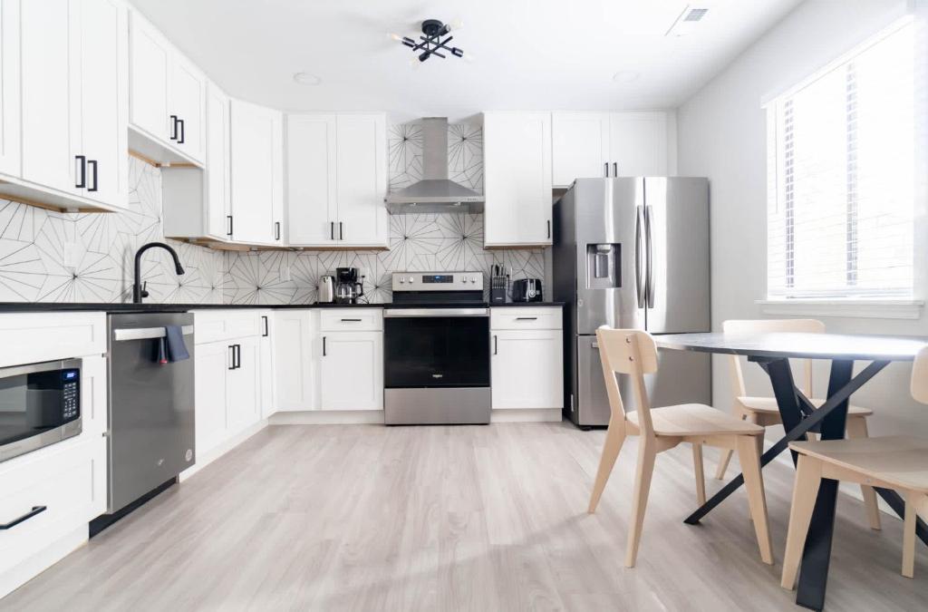 a kitchen with white cabinets and a table with chairs at The Vibe on Durham XI 8788 in Durham