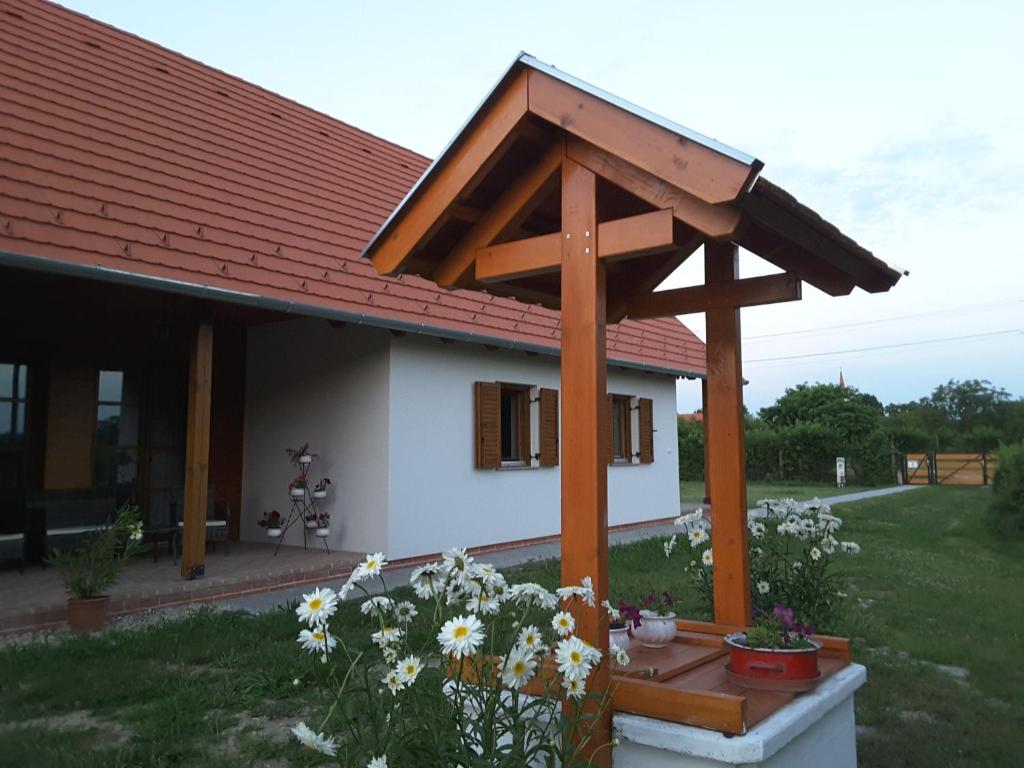 een klein huis met een grote houten pergola bij Malomkő Apartman in Zsira