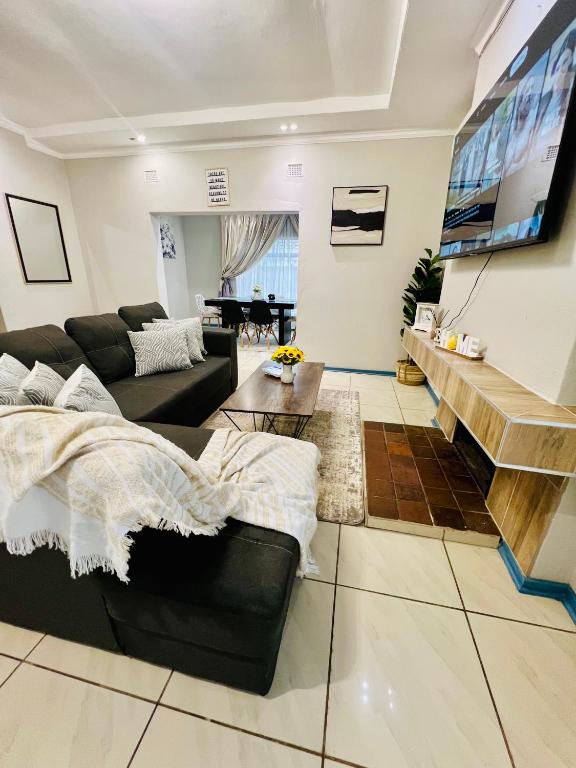 a living room with a black couch and a piano at The Treat Manzini in Manzini