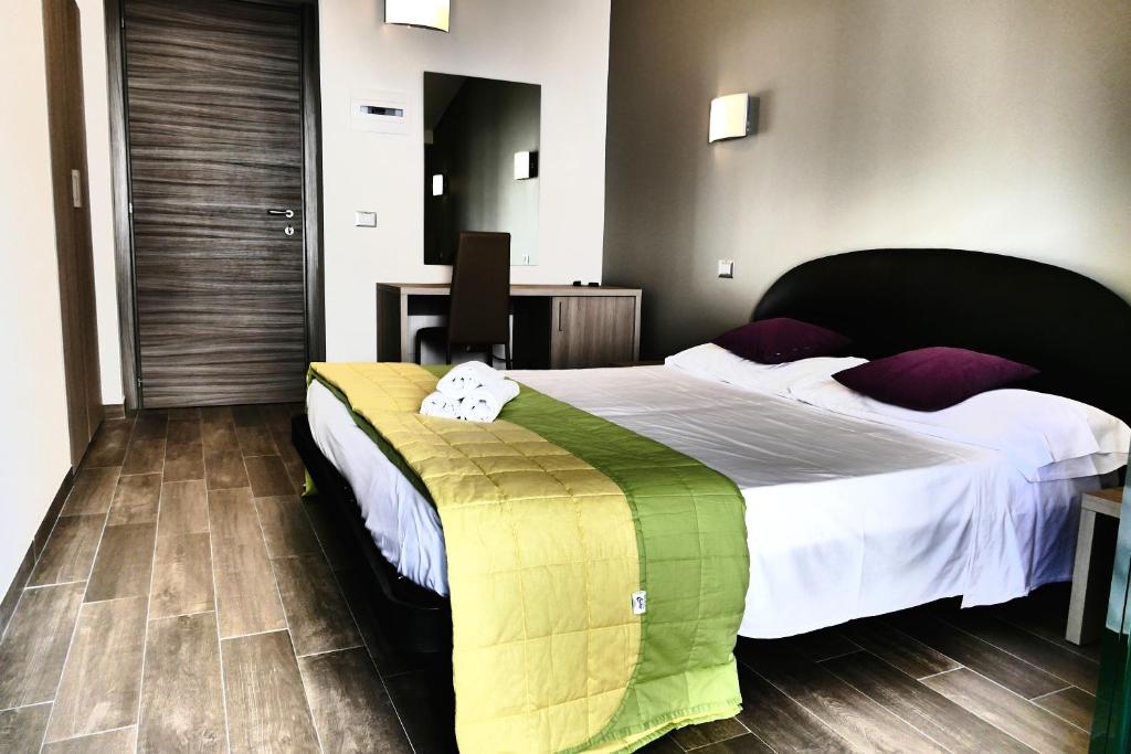 um quarto com uma cama grande com lençóis brancos e almofadas roxas em Hotel Désirée em San Benedetto del Tronto